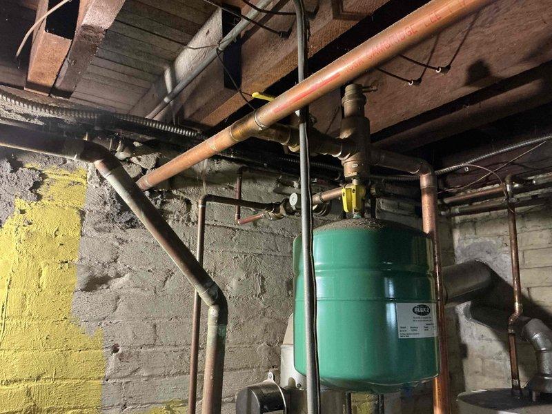 Conducted on-site estimate for boiler system replacement in residential basement mechanical room. Upon inspection, documented existing heating infrastructure including green expansion tank, copper supply piping, and white furnace unit with associated venting system. Assessed current equipment configuration, photographed mechanical components, and provided homeowner with replacement options and recommendations for new boiler installation.