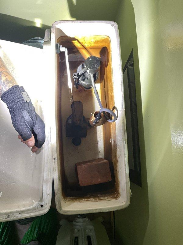 Responded to water leak investigation in 1920s-era residential property. Upon inspection, identified toilet tank as source of leak with significant water damage to surrounding wooden framing and structural components. Tank interior showed extensive brown water staining, mineral deposits, and discolored water indicating chronic leak and corrosion of flush valve assembly. Documented deteriorated wooden framing compromised by long-term moisture exposure, rust staining on metal components, and sediment buildup in tank bottom. Recommended replacement of corroded flush valve system and repair of water-damaged structural framing to prevent further deterioration.