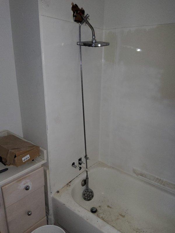 Responded to follow-up service call for persistent low water pressure issue previously assessed in May. Technician arrived early morning to diagnose and address water pressure concerns affecting both bathroom and kitchen fixtures. Upon inspection, examined shower assembly, bathtub fixtures, and kitchen sink plumbing system. Investigated potential causes including clogged aerators, partially closed shut-off valves, and sediment buildup in supply lines. Assessed condition of existing plumbing infrastructure, including PVC drain lines and supply connections visible beneath kitchen sink cabinet. Documented current state of fixtures and plumbing components through photographic evidence showing bathroom shower system with vertical chrome piping and kitchen sink area with exposed under-cabinet plumbing. Confirmed water pressure levels at multiple fixtures to establish baseline measurements and identify affected areas throughout the property.