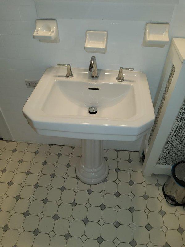 Repaired dripping bathroom faucet and replaced deteriorated supply line inside wall cavity behind pedestal sink. Accessed water supply lines through existing wall opening, installed new braided stainless steel supply line with proper fittings, and verified all connections were leak-free and operating correctly.