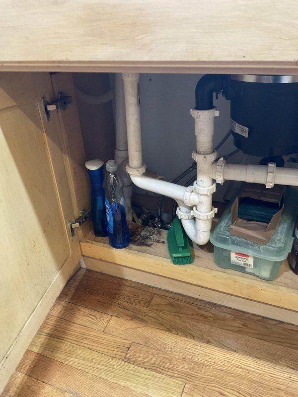 Responded to a clogged kitchen sink call and performed diagnostic inspection of the drainage system. Upon arrival, examined the P-trap assembly and associated PVC plumbing connections beneath the sink, which appeared to be in standard operational condition. Additionally inspected the vertical drain pipe where it exits through the floor, noting significant rust and corrosion buildup on the metal piping that may require future attention to prevent potential drainage issues or structural failure of the pipe.