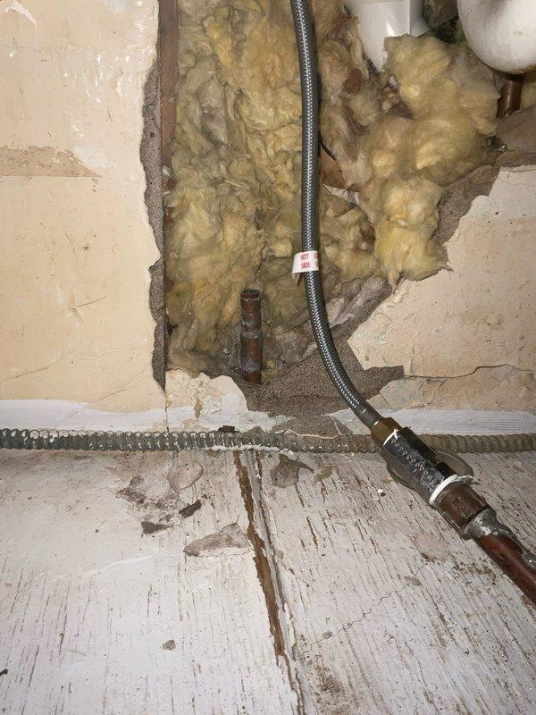 Responded to water leak at two-family rental property where leaking pipe had caused significant water damage to interior walls and ceiling. Accessed affected plumbing through opened wall section, exposing damaged pipe connections with visible oxidation on copper/brass fittings. Repaired leaking water line and flexible supply connections in wall cavity between insulation and studs. Documentation captured extent of water damage including ceiling paint deterioration, peeling, and moisture intrusion affecting multiple room surfaces, as well as compromised wall integrity requiring future cosmetic restoration by property owner.