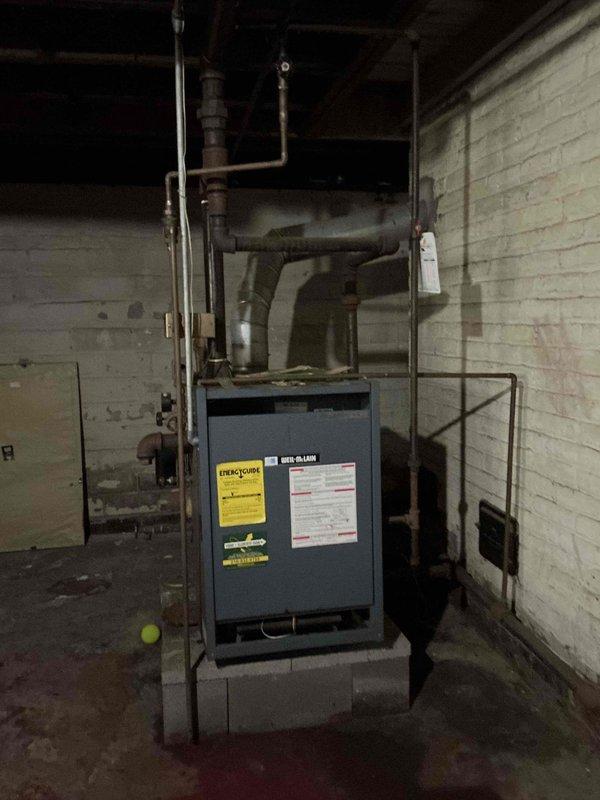 Completed comprehensive boiler inspection in mechanical room. System evaluated included blue residential boiler unit with associated piping network showing age-related wear and oxidation on multiple pipe runs. Documented current equipment condition, piping configuration, and overall system status through photographic records for maintenance planning purposes.