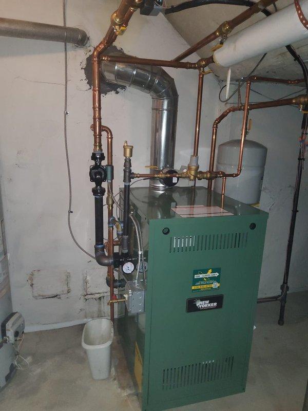 Completed installation of New Yorker model CG60F hot water boiler rated at 175,000 BTUs in basement mechanical room. Installation included new expansion tank, pressure reducing valve with backflow preventer, automatic air vent, circulator pump, and 3/4-inch zone valve for basement zone control. Modified all near-boiler piping with copper lines and brass fittings, installed new flue pipe to existing chimney, and mounted two new digital programmable thermostats for multi-zone temperature control. All components tested and operational upon completion.