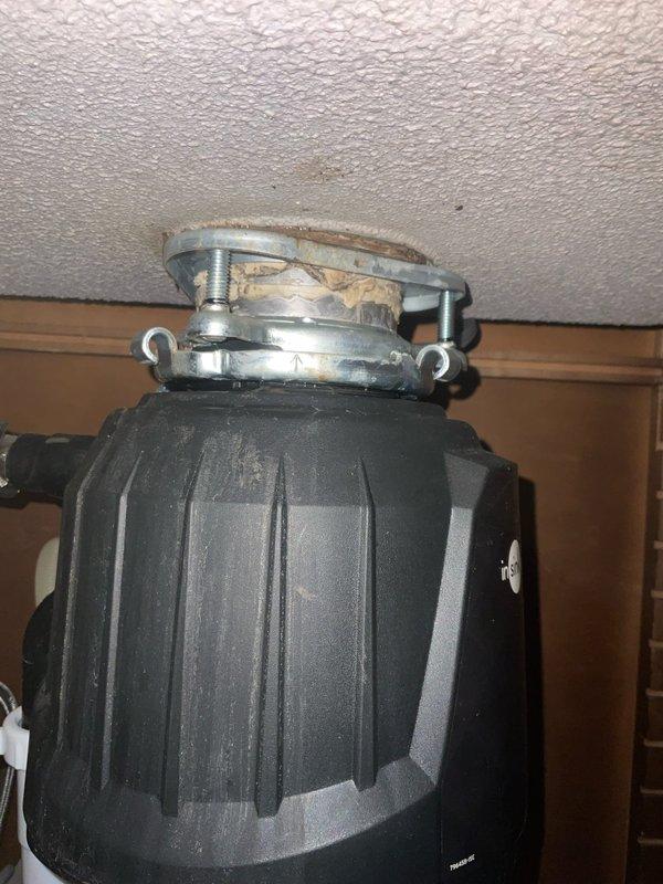 Responded to kitchen sink leak complaint and performed thorough inspection of under-sink plumbing system. Upon examination, identified leak originating from InSinkErator garbage disposal unit mounting assembly. Inspected mounting flange, gasket seal, and connection points between disposal and sink drain. Tightened mounting hardware and verified all metal clamp rings and brackets were properly secured. Tested system for leaks and confirmed repair resolved the issue.