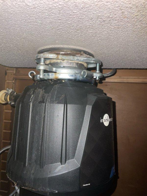 Responded to kitchen sink leak complaint and performed thorough inspection of under-sink plumbing system. Upon examination, identified leak originating from InSinkErator garbage disposal unit mounting assembly. Inspected mounting flange, gasket seal, and connection points between disposal and sink drain. Tightened mounting hardware and verified all metal clamp rings and brackets were properly secured. Tested system for leaks and confirmed repair resolved the issue.