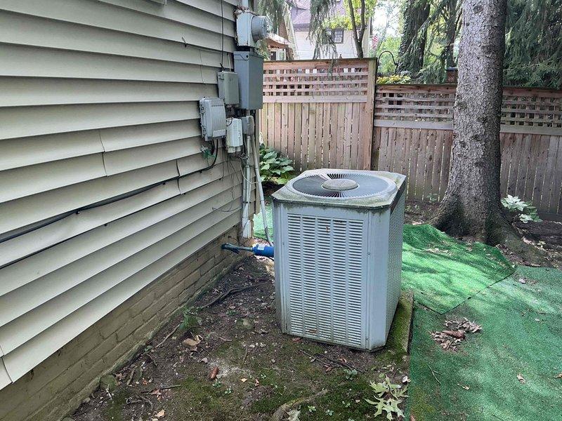 Performed estimate for complete HVAC system replacement on 24-year-old furnace and air conditioning unit presenting with no cooling condition. Assessed XL 80 furnace in basement utility space with associated humidifier and ductwork, along with outdoor cylindrical condenser unit showing significant age-related deterioration including surface discoloration and biological growth. Recommended full system replacement due to age of equipment exceeding expected service life and current system failure.