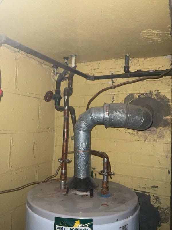 Responded to service call for active water leak on existing tanked water heater. Upon inspection, identified slow leak from aging water heater unit with visible corrosion on piping connections and deteriorated valve components. Assessed installation showing considerable age with oxidized copper supply lines, corroded gas piping, and weathered exhaust venting. Documented existing conditions including compromised pipe fittings, mineral deposits, and general wear on plumbing infrastructure. Evaluated water heater tank integrity and connection points to determine source of active leak and provided customer with findings and repair recommendations.