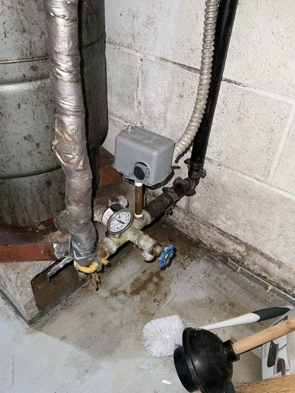 Conducted free estimate for water softener installation in basement utility area. Assessed existing plumbing configuration including current pressure tank, filtration system, and piping layout to determine optimal placement and integration requirements for new water softening equipment. Documented existing conditions showing signs of hard water damage, corrosion on pressure vessel, and floor moisture staining, confirming need for water treatment solution.