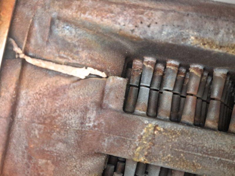 Performed routine maintenance inspection on a 7-year-old hot water boiler system. Documented extensive corrosion and rust present on burner assembly components and associated piping, with visible oxidation on metal tubes and deterioration of heating elements against refractory brick surfaces. Confirmed operational status of unit at time of service visit.