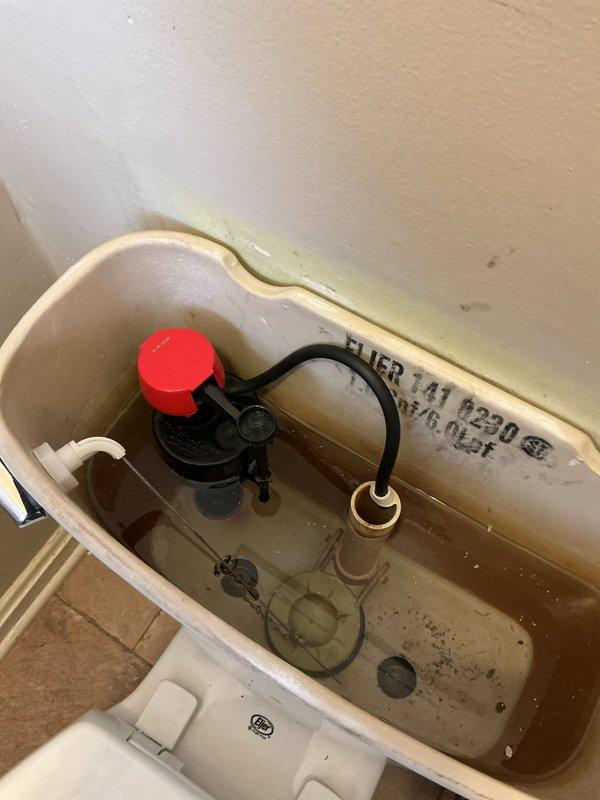 Responded to reported leak in cast iron soil pipe system. Upon arrival, conducted comprehensive inspection of plumbing fixtures and components. Examined toilet tank assembly, noting typical wear patterns and mineral deposits consistent with regular use. Inspected fill valve mechanism with functioning red-capped assembly and flush valve components showing normal operational condition. Evaluated water supply line connections and floor-mounted shutoff valve for signs of active leakage or deterioration. Assessed bathroom ventilation grille showing corrosion and rust staining, indicating potential moisture-related issues in the area. Documented all findings with photographic evidence for service records. All accessible plumbing connections and fixtures were visually inspected for active water intrusion.