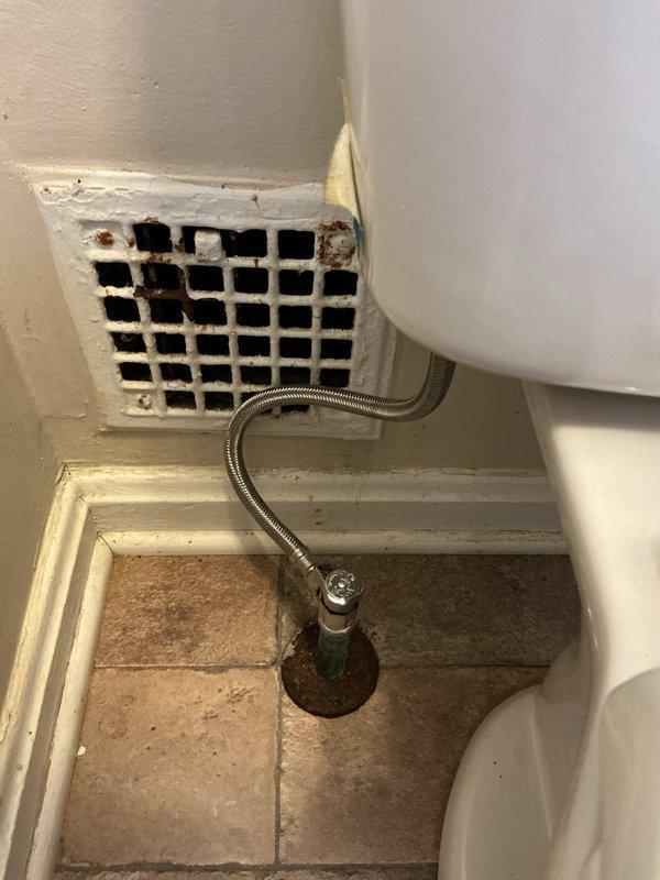 Responded to reported leak in cast iron soil pipe system. Upon arrival, conducted comprehensive inspection of plumbing fixtures and components. Examined toilet tank assembly, noting typical wear patterns and mineral deposits consistent with regular use. Inspected fill valve mechanism with functioning red-capped assembly and flush valve components showing normal operational condition. Evaluated water supply line connections and floor-mounted shutoff valve for signs of active leakage or deterioration. Assessed bathroom ventilation grille showing corrosion and rust staining, indicating potential moisture-related issues in the area. Documented all findings with photographic evidence for service records. All accessible plumbing connections and fixtures were visually inspected for active water intrusion.