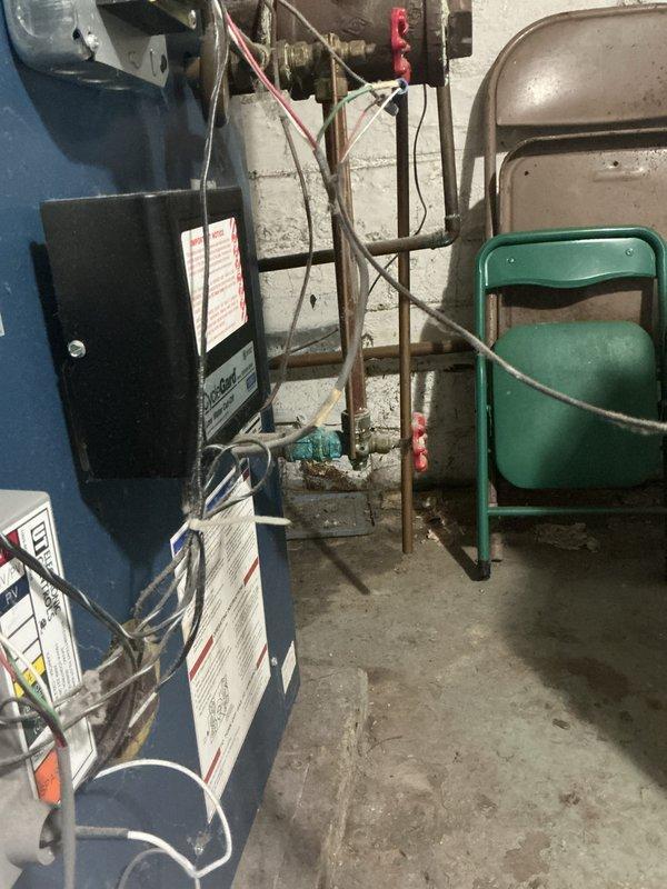 Completed winter maintenance tune-up on hydronic boiler system in utility room. Performed comprehensive inspection of boiler components, burner assembly, and heat exchanger; checked all safety controls and operating pressures. Noted corrosion present on horizontal piping connections with standing water in drain pan beneath system, indicating potential slow leak or condensate drainage issue that should be monitored.
