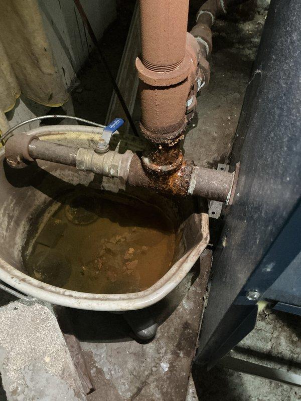 Completed winter maintenance tune-up on hydronic boiler system in utility room. Performed comprehensive inspection of boiler components, burner assembly, and heat exchanger; checked all safety controls and operating pressures. Noted corrosion present on horizontal piping connections with standing water in drain pan beneath system, indicating potential slow leak or condensate drainage issue that should be monitored.