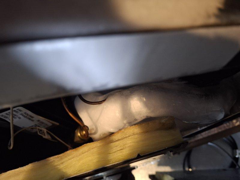 Responded to service call for one-year-old air conditioning system in basement with active water leakage, standing water on unit, condensation dripping from pipes, and saturated flooring. Upon inspection, found evaporator coil completely frozen with significant ice buildup on refrigerant lines and fittings, preventing proper system operation and causing loss of cooling capacity. Documented frozen coil condition and ice formation on copper refrigerant lines through photography. Advised system requires complete thaw cycle before diagnostic testing can be performed to determine root cause of freeze-up, which may include restricted airflow, low refrigerant charge, or failed blower motor. Scheduled follow-up appointment to complete diagnostic evaluation and necessary repairs once unit has fully defrosted.