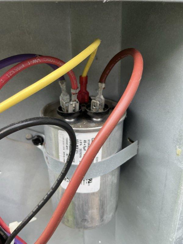 Responded to service call for non-operational 2-year-old central air conditioning system. Upon inspection, discovered severe thermal damage to capacitor wiring, with yellow wire insulation melted and charred, exposing bare conductor. Replaced failed dual-run capacitor and damaged wire connections. System tested successfully and restored to full operation.