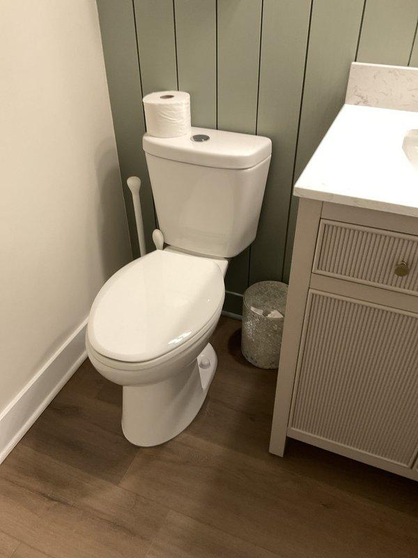 Conducted site assessment for bathroom plumbing upgrades. Evaluated existing water line routing to provide estimate for re-running supply line. Inspected toilet for removal and replacement, documenting current fixture condition and surrounding flooring. Assessed shower area for handicap grab bar installation, noting tile wall construction and optimal placement locations near tub/shower entry. Photographed all work areas including shower with marble-pattern tile walls and existing fixtures, toilet area with adjacent vanity, and surrounding bathroom infrastructure to support detailed estimate preparation for proposed plumbing modifications and accessibility improvements.