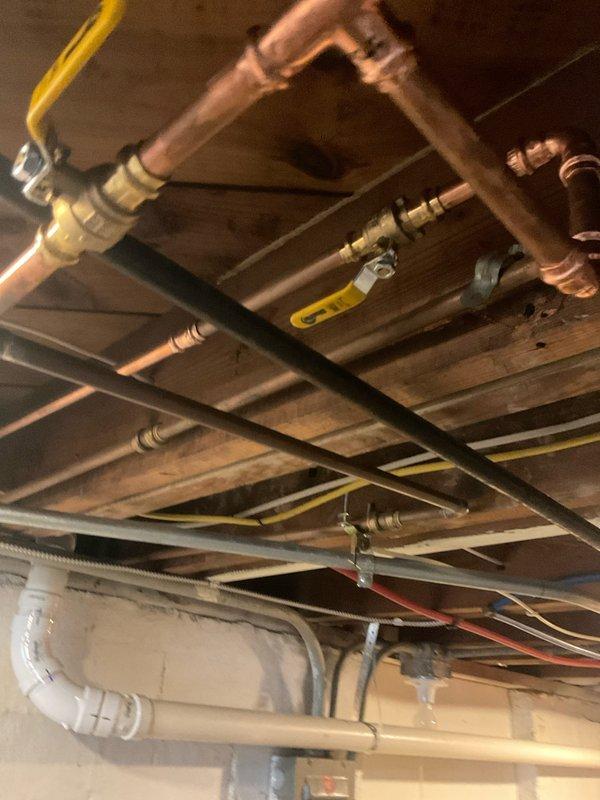 Removed existing galvanized water supply line from meter to copper transition point and replaced with PEX piping system. Installed 30 feet of 1/2" blue PEX with brass adapters and fittings, including a 1/2" brass 90-degree elbow on the riser under stairs. Abandoned existing cold water galvanized line from utility tub and rerouted supply from main trunk line to front exterior spigot. Installed new frost-free hose bib at exterior location. Completed installation included three 1/2" PEX 90-degree fittings, two male adapters, one 1/2" brass 90-degree elbow, one 1/2" brass plug, and three 1/2" press valves for shutoff capability throughout the system.