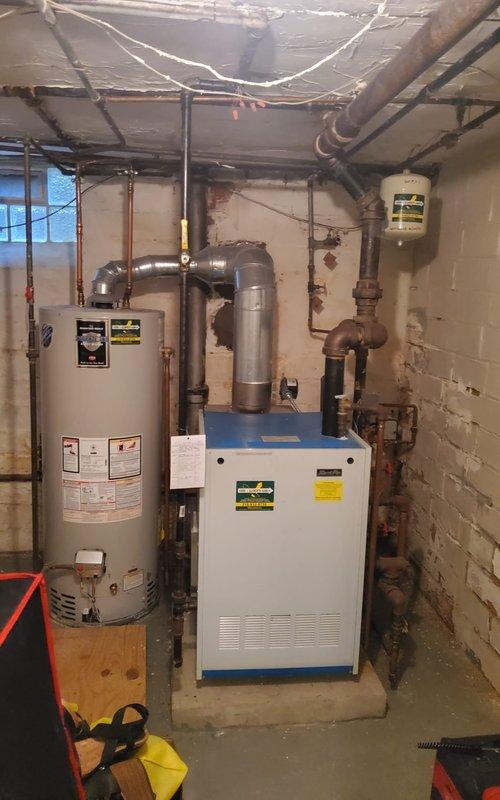 Completed scheduled maintenance on residential steam boiler system located in basement mechanical room. Performed comprehensive inspection of boiler unit, burner assembly, and associated piping systems. Verified proper burner operation with all tubes firing correctly, displaying appropriate flame characteristics with blue and orange combustion patterns. Inspected gas manifold connections, supply lines, and safety controls for proper function. Examined steam distribution piping, condensate return lines, and pressure relief systems. All components found operating within normal parameters with no immediate safety concerns identified.
