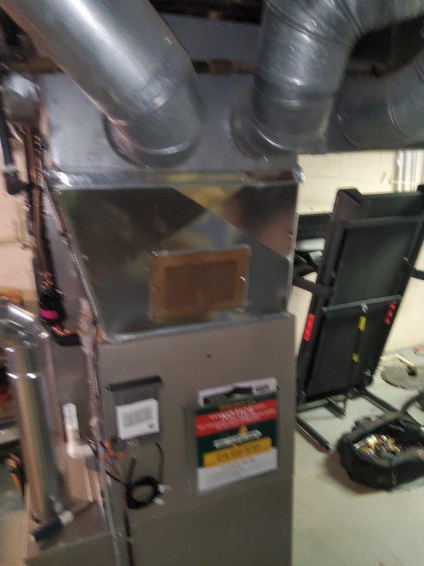 Completed full HVAC system installation in residential basement, including new furnace unit, evaporator coil, air conditioning system, and thermostat. Installed gray metal air handler with proper refrigerant line connections featuring copper lines with black insulation, connected flexible metallic ductwork to distribution plenum, and mounted electrical control panel with operational indicators. All equipment properly positioned on concrete floor with PVC condensate drainage line routed appropriately, system tested and verified operational upon completion.