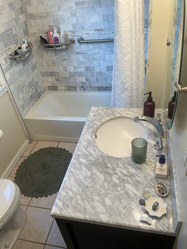Responded to service call for slow-draining shower in residential bathroom. Upon arrival, inspected shower/tub combination with glass enclosure and identified drainage issue. Assessed plumbing fixtures, drain assembly, and water flow patterns to determine cause of blockage. Provided detailed estimate for drain clearing and repair options to restore proper drainage function. Documented existing bathroom conditions including tiled shower surround, chrome fixtures, and vanity area for service records.