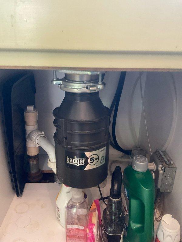 Responded to kitchen sink drainage issue with water backing up into dishwasher. Upon inspection, identified clog in drain line connected to Badger 5+ garbage disposal unit. Cleared obstruction from drain system, verified proper water flow through disposal and dishwasher connection, and tested all plumbing connections under sink to ensure no leaks. System restored to normal operation with proper drainage confirmed.