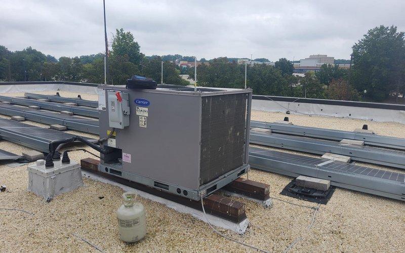 Responded to no cooling call for 2-year-old Carrier rooftop AC unit. Upon arrival, inspected rooftop installation and confirmed unit was not operating. Diagnosed low refrigerant charge caused by leak in system. Located leak, performed necessary repairs, evacuated system, and recharged unit to manufacturer specifications. Verified proper cooling operation, temperature differential, and all safety controls before completing service call.