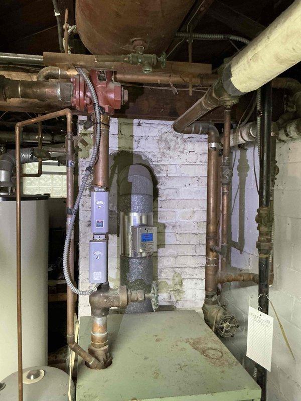 Conducted estimate for replacement of aging residential boiler system in basement mechanical room. Assessed existing light green boiler unit with associated copper piping network, expansion tank, circulator pump, and zone valves showing significant wear and oxidation consistent with extended service life. Documented current system configuration including connection points, venting arrangement with PVC flue pipe, pressure tank placement, and integration with existing hydronic heating distribution system. Photographed equipment condition, piping layout, and installation environment to prepare comprehensive replacement proposal. Provided homeowner with equipment options and scheduling recommendations for system replacement.