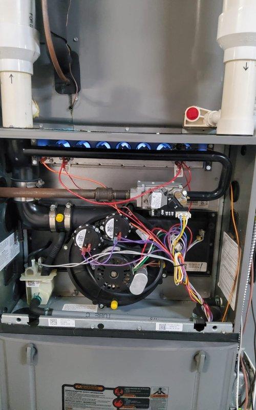 Performed comprehensive pre-winter inspection on 12-year-old residential furnace system. Upon arrival, conducted visual assessment of unit with access panel removed to examine internal components. Inspected burner assembly, heat exchanger, blower motor, and all electrical connections. Noted operational components including gas burner rack with blue flame operation, blower assembly with motor housing, and PVC venting system with proper directional flow indicators.

Examined electrical system including capacitor, contactor, and associated wiring connections. Observed evidence of significant deterioration on outdoor electrical components, including rust staining, corrosion on metal panels, and charred debris accumulation indicating previous electrical arcing or burning at contactor assembly. Documented condition of all colored wire connections (red, purple, yellow, orange, blue, green, and pink) throughout control system.

Verified all safety labels and specification plates remained legib