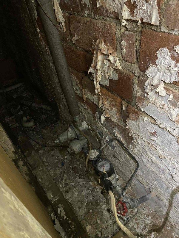 Responded to emergency service call for boiler overflow and complete loss of water supply to residence. Upon arrival, investigated 20-25 year old boiler system in basement and confirmed that automatic fill valve was left in open position, causing extensive water overflow throughout the area. Inspected plumbing connections and identified severely corroded and deteriorated pipe fittings at the water supply line that required immediate replacement. Documented extensive water damage to basement floor and walls, including moisture infiltration and degraded surfaces. Traced water supply issue and determined that main water supply had been shut off, likely as emergency response to the overflow condition. Marked failed components for replacement and provided assessment of aged plumbing infrastructure showing significant corrosion and end-of-service-life deterioration. Photographed conditions for documentation purposes.