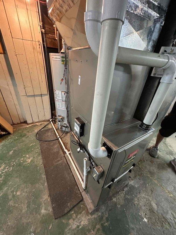 Completed full HVAC system replacement in basement utility area, including removal of existing equipment and installation of new furnace, evaporator coil, air conditioning unit, and thermostat. Installed gray metal furnace on concrete floor with proper clearances and connected large-diameter metal ductwork extending to upper air handler components, securing all connections with metal bands per manufacturer specifications. Mounted evaporator coil in appropriate position within duct system to ensure optimal airflow and refrigerant distribution.

Connected new air conditioning condenser unit to system with proper refrigerant lines and electrical connections. Installed new programmable thermostat and verified communication with HVAC equipment. Addressed airflow concerns for upstairs zone by evaluating existing vent configuration and installing additional return vent on back side of system to improve air circulation and balance throughout home.

Performed comprehensive system startup proced