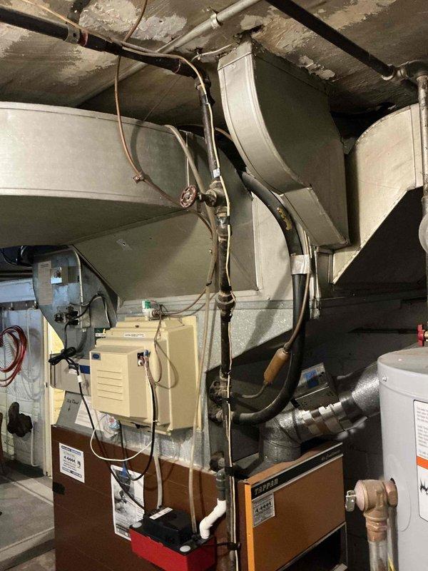 Completed estimate for replacement of 60+ year old furnace that was previously red-flagged and shut down due to safety concerns. Customer requested permits be included with the replacement proposal. Documentation and photos taken of existing equipment configuration, including outdated heating unit, ductwork system, water heater, and associated mechanical components in basement utility area.