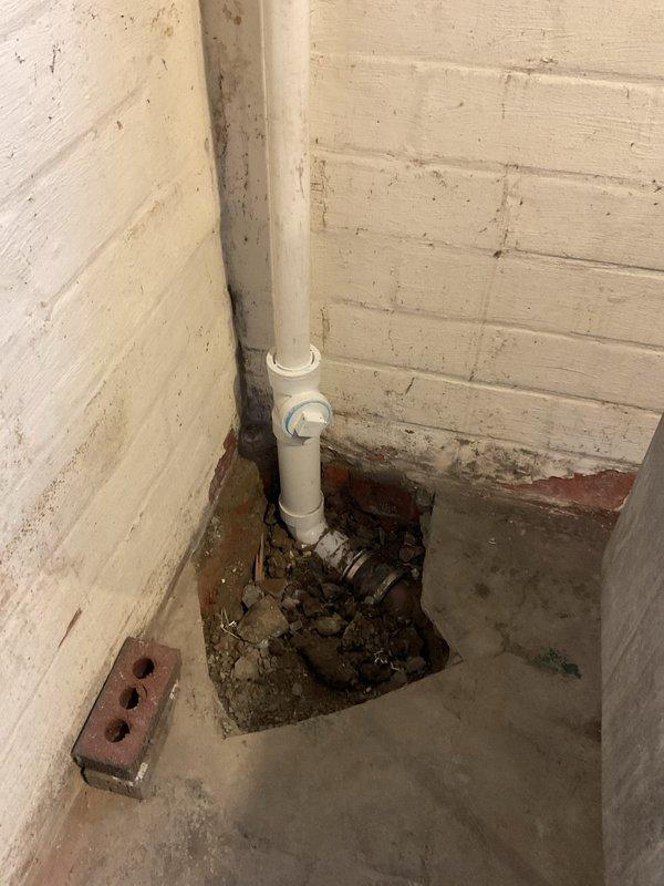 Completed kitchen sink drain replacement at residential property. Two-person crew successfully removed existing deteriorated drain assembly and installed new PVC drainage system. Work included addressing significant floor deterioration and water accumulation issues discovered at the base of the existing vertical drain pipe in the basement utility area. Cleared debris and standing water from affected concrete floor section, ensuring proper drainage flow and structural integrity of new installation. All components installed to code specifications with secure connections and proper sealing to prevent future moisture infiltration.