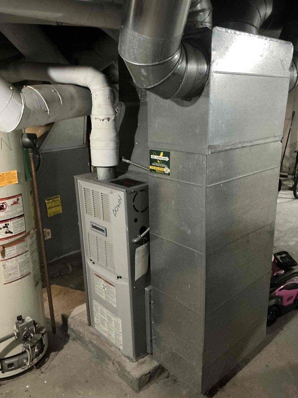 Conducted furnace replacement estimate for residential forced-air heating system located in basement mechanical room. Assessed existing gray metal furnace unit with connected ductwork, PVC condensate drainage lines, and galvanized plenum, documenting current equipment configuration and installation requirements for replacement unit.