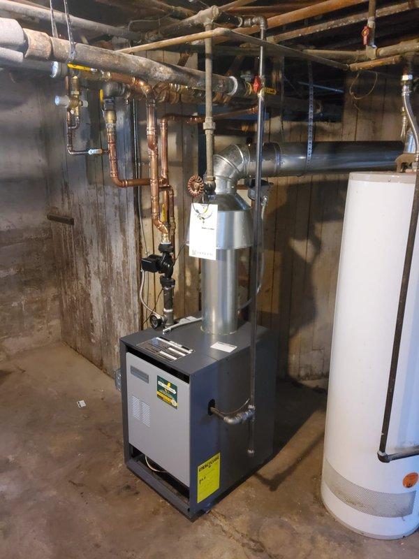 Completed installation of Weil McLain CGA-6 hot water boiler system in basement mechanical room. Installation included mounting and connecting new boiler unit, expansion tank, pressure reducing valve, backflow preventer, automatic air vent, and circulator pump with all necessary near boiler piping modifications using copper pipe. Installed new flue pipe venting to existing chimney, ran dedicated electrical circuit for boiler operation, and mounted new digital programmable thermostat for system control. All components tested and verified operational upon completion.