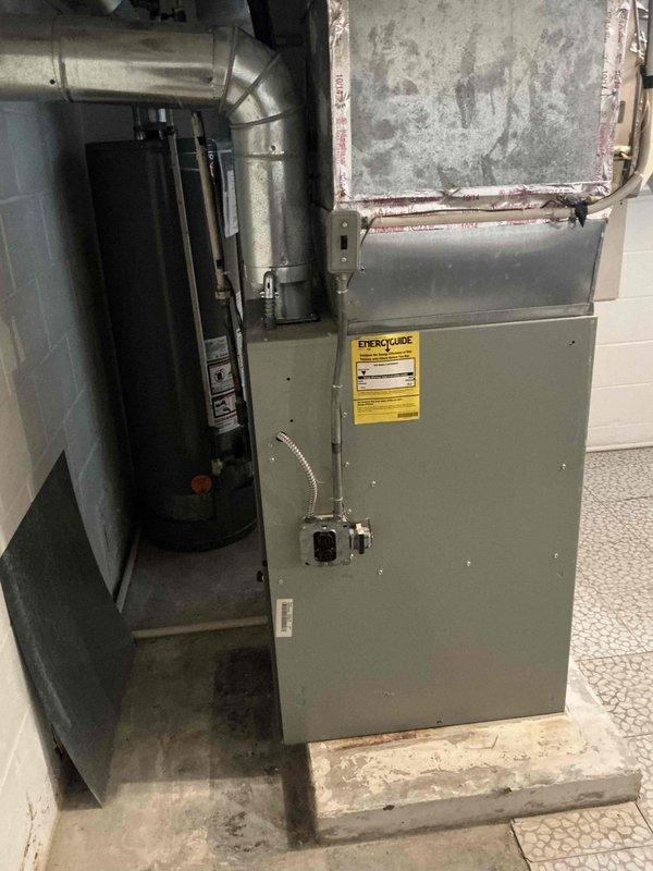 Conducted furnace replacement estimate for 26-year-old American Standard unit located in basement utility room. Documented existing equipment configuration including furnace, ductwork connections, and surrounding mechanical systems with photographs for proposal preparation.