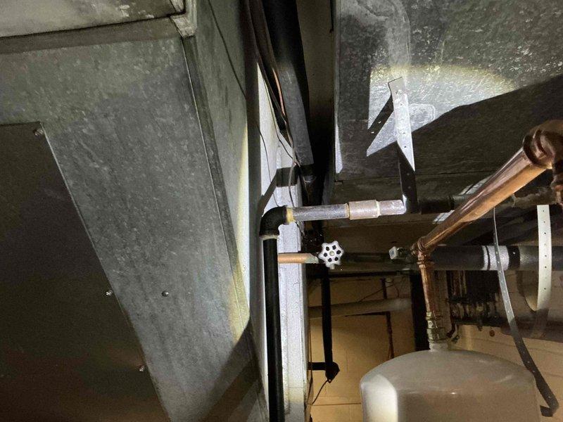 Removed non-functioning air cleaner unit from existing HVAC system and installed replacement ductwork to restore proper airflow. Modified sheet metal ductwork connections to integrate with existing copper piping and mechanical components in utility space, ensuring proper clearances around expansion tank and heating system elements.