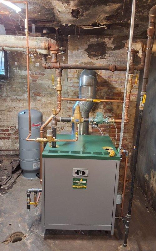 Completed full hot water boiler replacement in basement utility area. Removed existing heating system and installed new Peerless model 63-06 boiler rated at 175,000 BTU. Installation included new expansion tank, pressure reducing valve, backflow preventer, automatic air vent, and circulator pump. Performed all necessary near boiler piping modifications using copper pipe to integrate new components into existing hydronic heating system. Installed new flue pipe connection to chimney for proper venting. Upgraded system controls with new digital programmable thermostat. Tested all connections for leaks, verified proper combustion and system pressurization, confirmed circulator operation, and validated thermostat functionality. System commissioned and left in full operational condition.