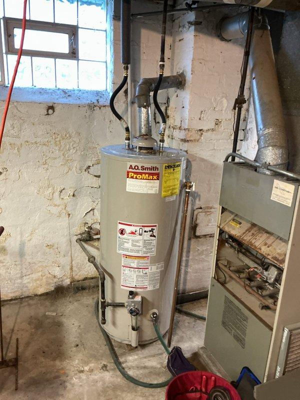 Responded to service call for tanked water heater leaking from top connections following recent tank flush. Upon inspection, found A.O. Smith ProMax water heater with significant corrosion and rust buildup at top fitting connections and center access panel, indicating long-term moisture exposure that likely worsened after flushing procedure disturbed sediment and stressed compromised fittings.