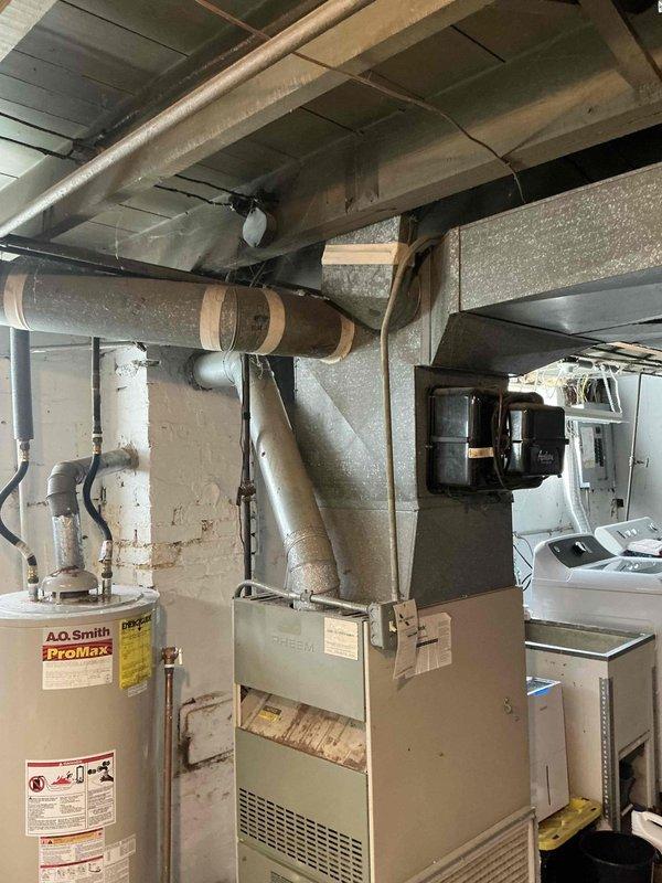 Responded to no-heat call on 35-year-old furnace and identified cracked heat exchanger requiring immediate replacement for safety. Provided customer with equipment replacement estimate and documented existing HVAC system configuration including furnace, ductwork, and surrounding mechanical equipment in basement utility area.
