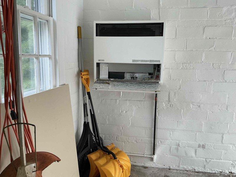 Completed estimate for garage heater replacement in white brick interior space. Assessed existing through-wall heating unit and provided multiple equipment options for upgraded heating system. Documented current installation configuration and discussed various heater models suitable for the space requirements and customer preferences.