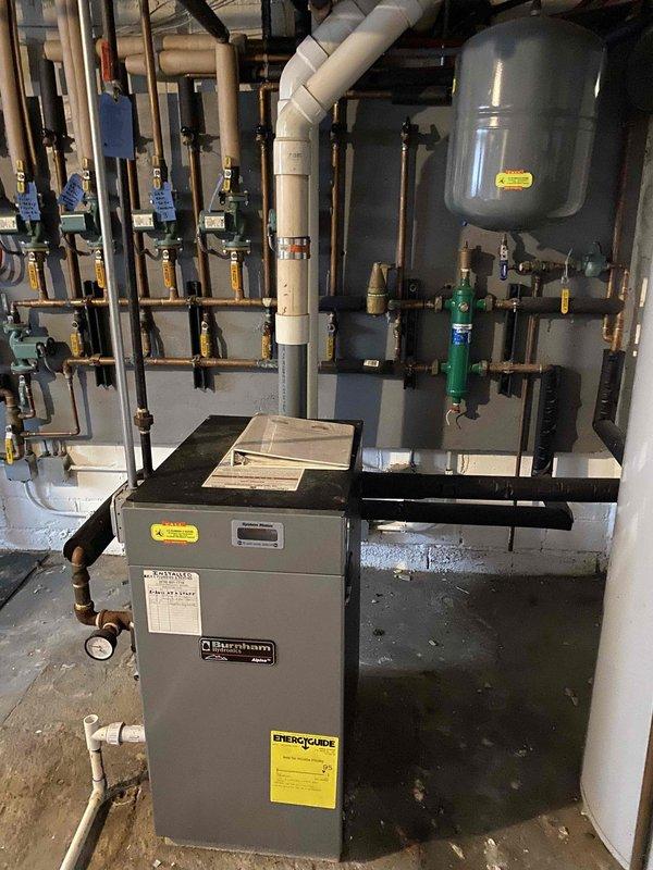 Conducted on-site assessment of 15-year-old Burnham Alpine boiler system to provide repair estimate. Performed comprehensive inspection of heating unit, associated piping network, expansion tank, zone valves, and system connections. Documented equipment condition including pressure gauge readings, valve operations, and overall system configuration. Photographed installation showing multi-zone piping arrangement with copper supply lines, expansion tank mounting, and boiler connections for customer records and repair planning purposes.