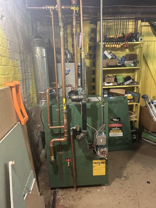 Completed full boiler replacement in basement utility room, installing New Yorker model CG60F hot water boiler rated at 175,000 BTUs. Installation included new expansion tank, pressure reducing valve, backflow preventer, automatic air vent, and circulator pump with all associated near-boiler piping modifications using copper pipe and brass fittings. Ran new flue pipe to existing chimney connection and installed new digital programmable thermostat for system control. All components tested and operational upon completion.