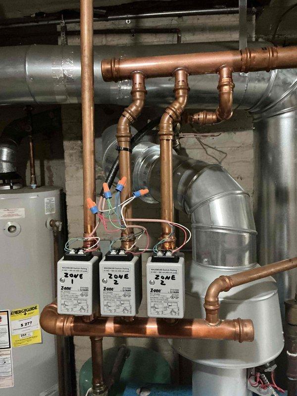 Completed scheduled maintenance on a 4-year-old gas-fired boiler system with multi-zone hydronic heating distribution. Inspected manifold assembly with three zone valves, verified proper operation of circulator pumps, examined copper piping connections and fittings for leaks, and assessed integrated HVAC ductwork components. All equipment found operating within normal parameters with no immediate service needs identified.