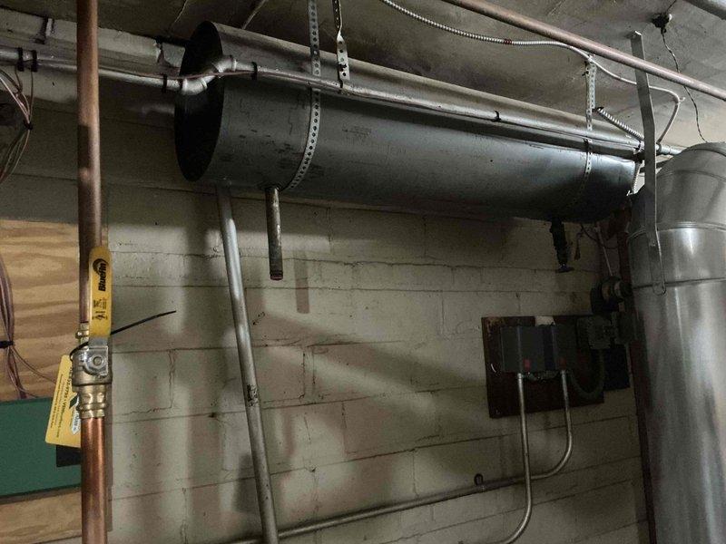 Completed scheduled maintenance on a 4-year-old gas-fired boiler system with multi-zone hydronic heating distribution. Inspected manifold assembly with three zone valves, verified proper operation of circulator pumps, examined copper piping connections and fittings for leaks, and assessed integrated HVAC ductwork components. All equipment found operating within normal parameters with no immediate service needs identified.