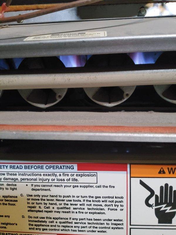 Responded to customer complaint of furnace blowing ambient air without heat. Upon inspection, found burner assembly igniting properly with normal blue flame pattern and adequate combustion. Verified gas valve operation, flame sensor functionality, and all safety controls operating within manufacturer specifications. System now heating properly and cycling normally.