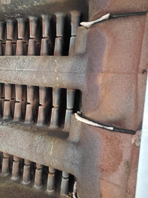 Completed scheduled boiler maintenance under home plan agreement. Thoroughly inspected heat exchanger components, including primary heat exchanger fins and secondary heat exchanger drum assembly. Both heat exchangers showed significant rust accumulation and corrosion on metal surfaces, indicating extended service life and exposure to moisture during normal operation. Documented current condition of copper-alloy fins and cylindrical pin-type heat exchanger with photographic evidence for maintenance records. All components remain functional despite visible oxidation and patina buildup typical of aging boiler systems.