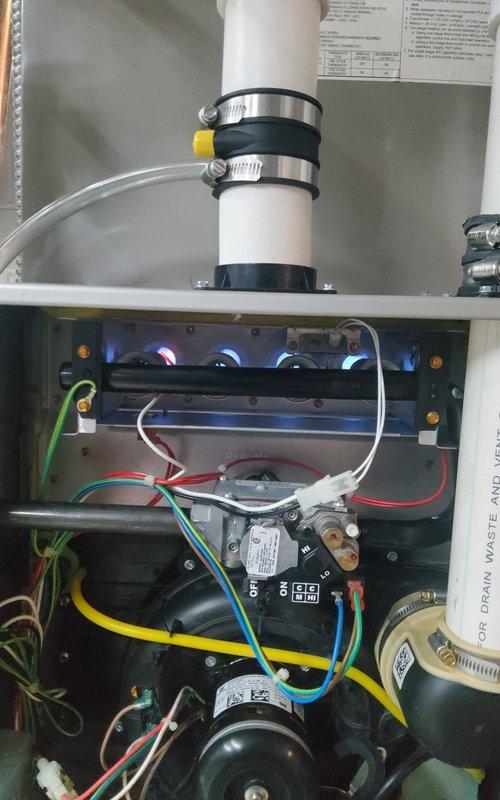 Completed comprehensive heating maintenance on two gas furnace systems and inspected Aprilaire humidifier. Performed diagnostics on 7-year-old gas furnace using multi-zone temperature meter, measuring supply and return air temperatures across multiple zones with readings ranging from 13°F to 93°F to verify proper heat exchanger operation and temperature rise. Inspected burner assembly operation, confirming proper blue flame combustion pattern across all burner heads with appropriate flame carryover. Verified blower motor operation, checked all electrical connections and safety controls including pressure switches, and examined venting system integrity with PVC exhaust piping properly secured with appropriate clamps. Evaluated gas valve operation, inspected wiring harnesses for proper connections, and confirmed all safety interlocks functioning correctly. Conducted visual inspection of humidifier unit to assess operational status and water delivery system.
