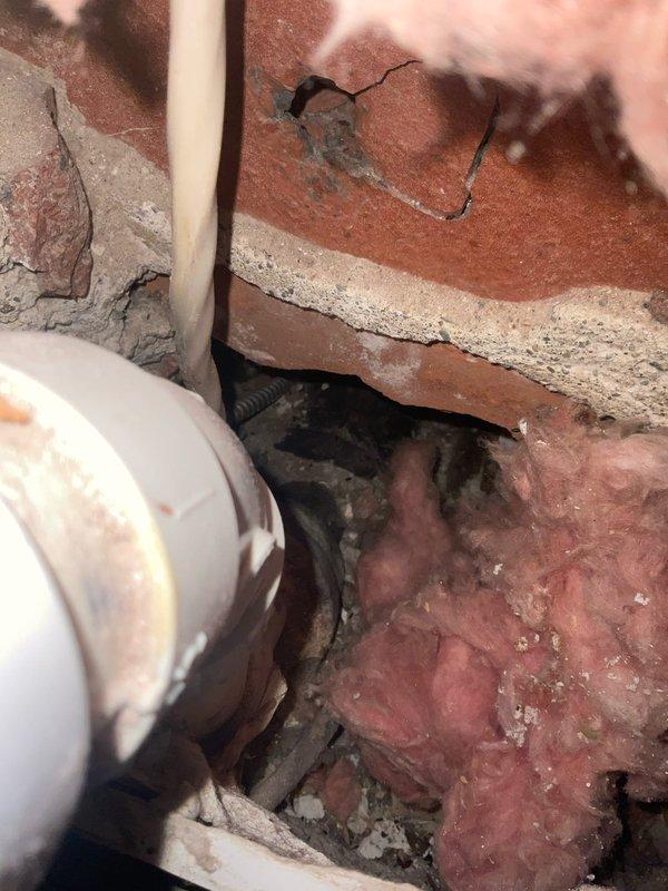Performed investigative leak detection work requiring selective demolition of interior walls and ceiling materials. Two-person crew opened multiple access points to trace active water intrusion through building envelope. Exposed interior wall cavities revealed compromised areas around plumbing penetrations, including deteriorated mortar joints in brick masonry and gaps in structural materials where PVC and metal piping passed through. Located source of leak at pipe penetration points where inadequate sealing and aged building materials allowed water infiltration. Documented existing conditions including damaged insulation, exposed wiring, and deteriorated concrete surfaces. Total duration of investigative work was two hours with photographic documentation completed for subsequent repair planning.