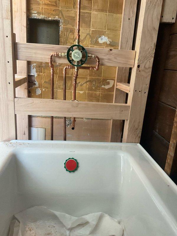 Installed customer-supplied valve on exposed copper plumbing assembly within bathroom wall framing during renovation. The installation included mounting the valve with integrated pressure gauge to the existing copper pipe T-configuration between wall studs, with all connections secured and tested for proper operation.